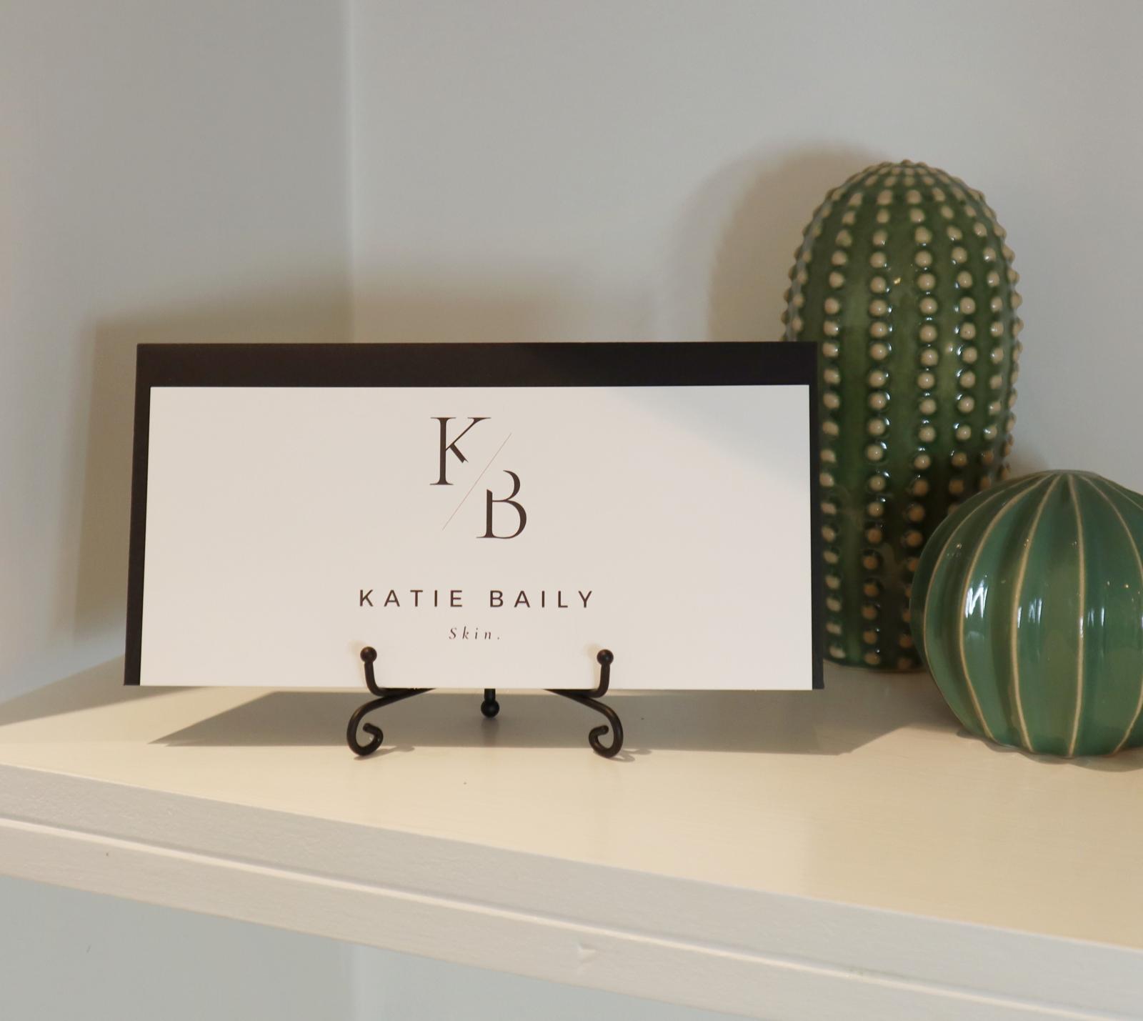 Katie Baily Skin’s framed logo displayed on a shelf